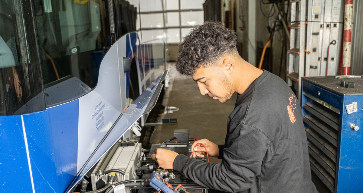 Ein Mitarbeiter arbeitet in einer Werkstatt an der Technik eines Scherer-Reisen Busses.