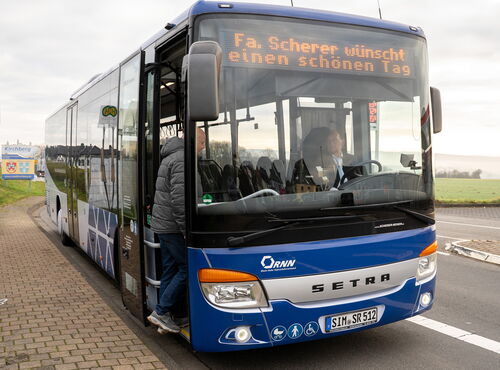 Mann steigt durch die Vordertür in einen blauen Linienbus von Scherer-Reisen.