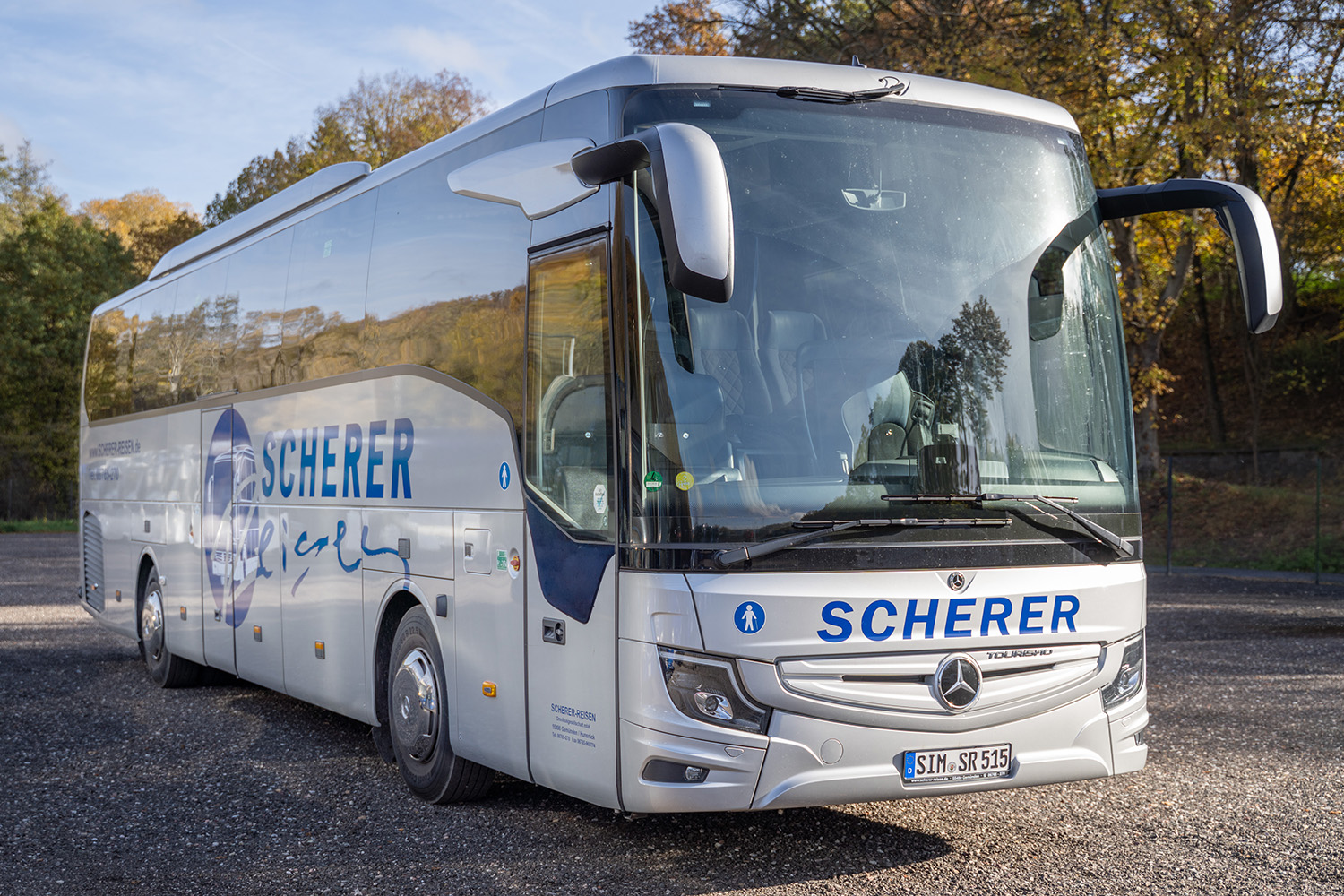 Schrägansicht eines silbernen Scherer-Reisen Reisebusses von vorn.
