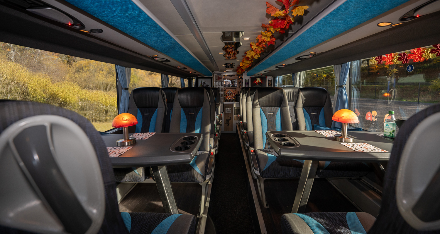 Innenraum von Saschas silbernen Doppeldeckerbus mit Tischen und herbstlicher Blätter-Dekoration.
